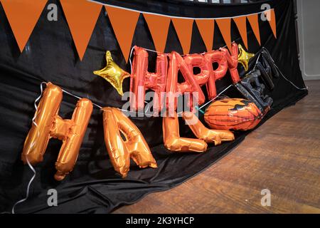 Happy Halloween orange balloon letters are prepared on the 2nd floor for hang on to the terrace with pumkin flag and black cloth background in Hallowe Stock Photo
