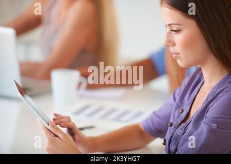 Typing an email. A gorgeous young creative businesswoman working on her digital touchpad. Stock Photo
