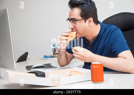 Man chilling have food while working and surfing the internet on his workstation. Stock Photo