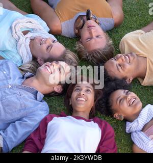 Everything is looking up. A group of young students lying on the grass on campus. Stock Photo
