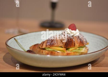 Sweet croissant and fruit slices on table, closeup. Stock Photo