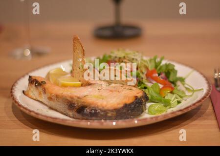 Close up of freshly fried salmon fish fillet with tomatoes, valerian, wheat germ and lettuce. Stock Photo