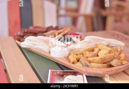 Plate with delicacies: wedges potato, garlic sauce, white bread and pitted black olives. Stock Photo
