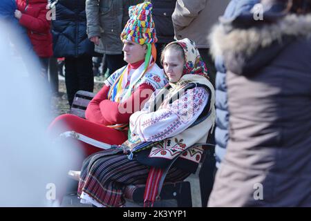 Two tired young people, dressed in romanian national costume at the winter festival. Authentic traditional from Romania Stock Photo