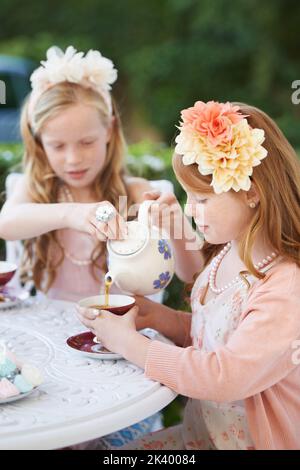 Fancy a spot of tea love. Two young girls having a tea party in the backyard. Stock Photo