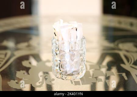 Thick glass cup filled with sugar sachets. Stock Photo