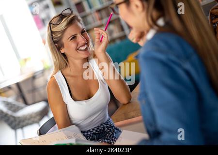 Happy young students studying and preparing for exam in college library. Education people concept Stock Photo