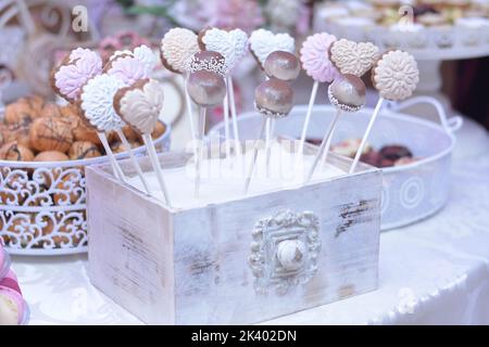 Various cake pops decorated with white, and dark chocolate on a white-pink background Stock Photo
