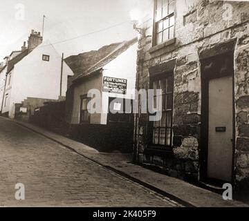An old photograph of the upper part of Henrietta Street, Whitby, North Yorkshire, UK , showing Fortune's kipper house and to its right is a former public house, possibly the Prince of Wales Stock Photo