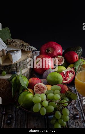 Served grapes, tangerines, figs, nectarines, blueberries, avocados, tangerines, limes and a glass of natural fresh juice with Brie, goat cheese and pe Stock Photo