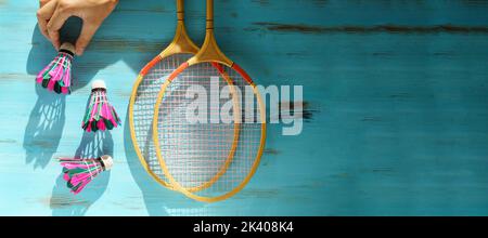 Shuttlecocks and badminton rackets on blue wooden background. Flat lay. Copy space Stock Photo