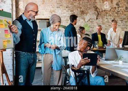 Multi-Ethnic office workspace room - Businesspeople meeting gather around the business model canvas - Diverse team of creative professionals talk, bra Stock Photo