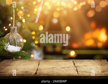 Empty wooden table on Christmas ornaments background with fireplace. Copy space. Stock Photo