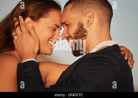 Love, summer and couple bonding on a beach holiday, embracing in intimate moment at sunset. Happy, face and man and woman relax and hug, talking and Stock Photo