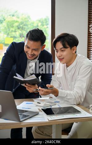 Portrait, Two happy and cheerful Asian businessmen or male financial analysts brainstorming and working together on their project. Stock Photo