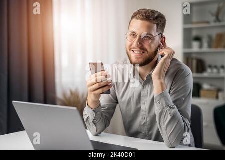 Happy smiling student use earphones for education, handsome man studying remotely from home, online listening course at laptop Stock Photo