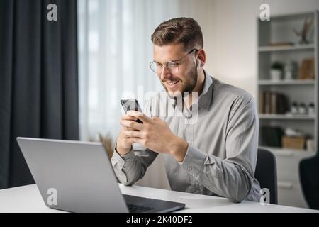 Happy smiling handsome man use smartphone for texting, student use app at home Stock Photo