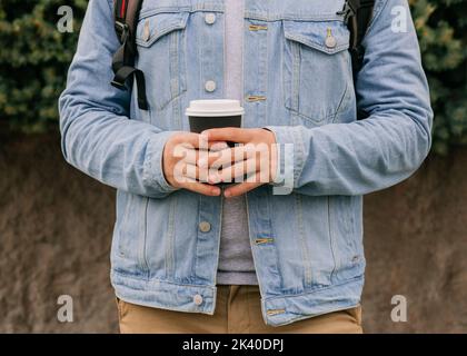 Unrecognizable man is holding black paper cup in his hands Stock Photo