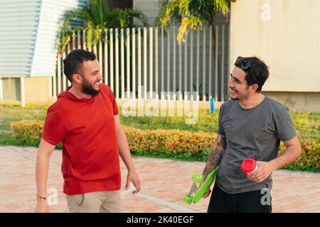 Two young Latino college students greeting each other in the park Stock Photo