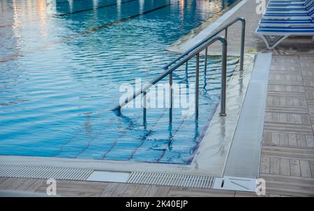 Stainless steel handrail and stairs into the swimming pool Stock Photo