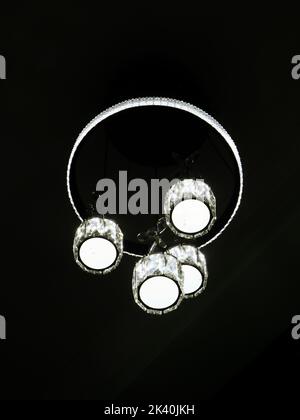 glowing round LED chandelier light on a black background in the ceiling Stock Photo