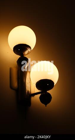 lamp with two bulbs of ambient yellow lighting on the wall in the dark of the night Stock Photo