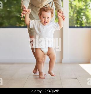 Development, walking and baby learning with mother helping support her childs growth, progress and first steps. Smile, happy and parent holding hands Stock Photo