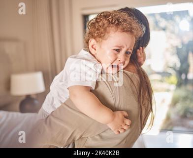 Crying, sad and tears of baby with mom for comfort, safety and attention while hungry, upset or tired in a family home. Toddler boy child cry while in Stock Photo