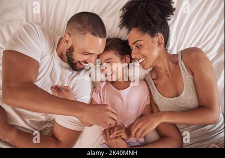 Morning, love and parents relax from above on bed with happy daughter together in Mexican house. Cheerful mother and father of young child smile in