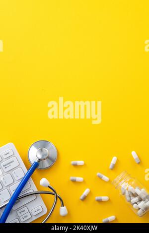 Doctor diagnoses design concept - stethoscope with computer keyboard and capsule pill on yellow background. Stock Photo