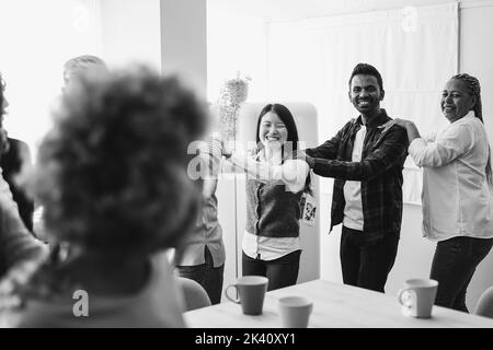 Multiracial happy friends having fun dancing at home kitchen - Main focus on indian man face - Black and white editing Stock Photo