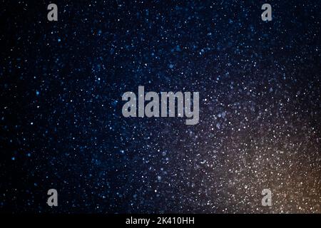 Organic dust particles floating on a colorful light beam on black background. Glittering sparkling flickering overlay. Stock Photo