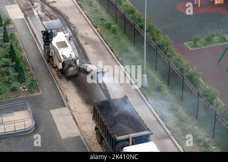 Asphalt milling machine working on the street. road surface milling in a residential area of the city Stock Photo