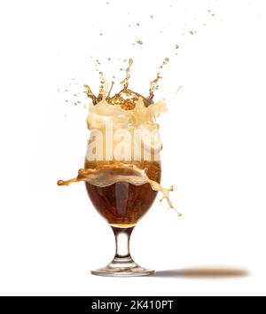 Ice cube falling into beer glass creating huge foam splashes. Glass with dark beer isolated on white background. Art, creativity, moment, details Stock Photo