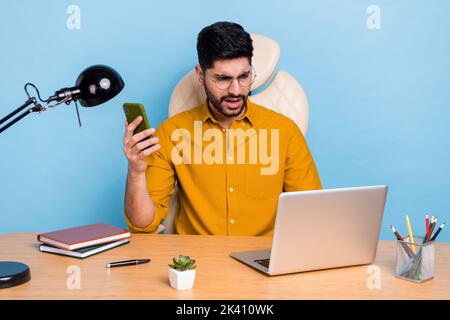 Photo of impressed person sitting chair hold telephone use wireless netbook isolated on blue color background Stock Photo