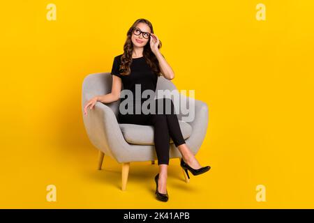 Full size photo of young pretty woman interested look empty space sit comfort recruiter isolated over yellow color background Stock Photo