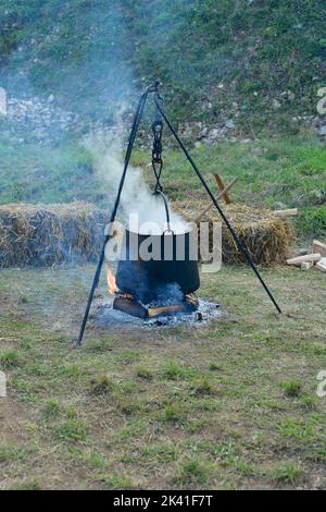 Food in a cauldron on a fire. Cooking outdoors in cast-iron cauldron. Stock Photo