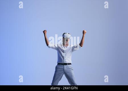 Successful businessman celebrating his victory in the metaverse. Mature businessman cheering while wearing a virtual reality headset. businessman work Stock Photo