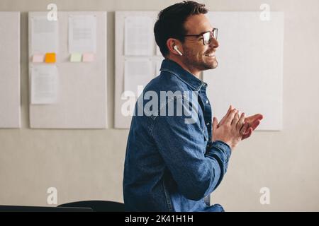 Cheerful businessman having a conference call using earbuds. Happy young businessman smiling while communicating with his team. businessman with glass Stock Photo