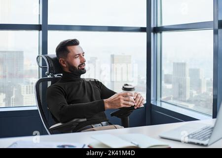 tired businessman drinks coffee sitting at his desk. Stock Photo