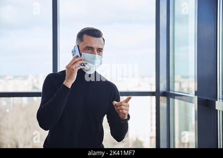 businessman with a smartphone standing near the window. Stock Photo