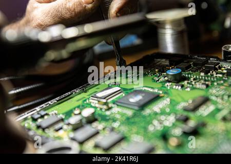 Car Ecu Detail with visible components with hand that repair it. Car ecu repair detail. Electronic board repair Stock Photo