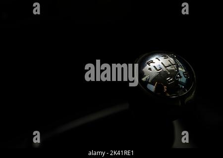 Gear shift lever of the car in the dark background. Image with copy space. Close up of top of gear stick in car interior Stock Photo