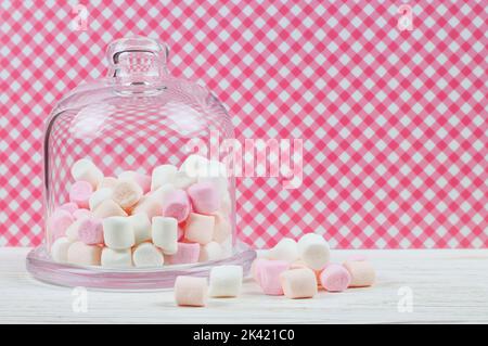 Pink marshmallow in a glass bell on red checkered background Stock Photo