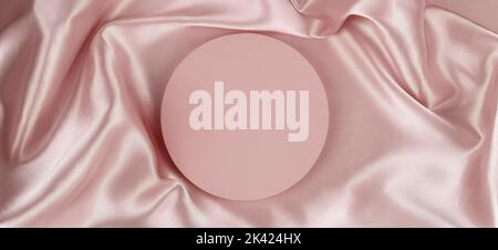 Geometric round platform podium on pale pink silk satin background. Blank minimal cylinder form mock up background for cosmetic product presentation Stock Photo