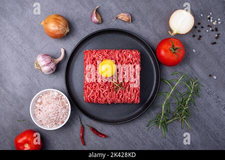 Minced meat lies on a black ceramic plate Stock Photo