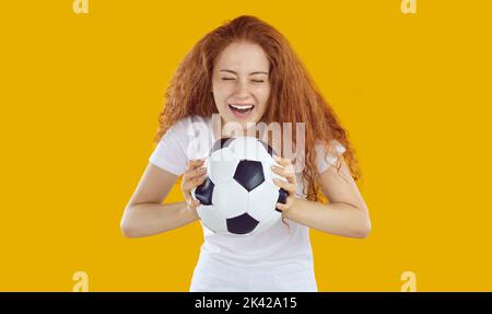 Happy cheerful pretty young woman or teenage girl holding soccer ball and laughing Stock Photo