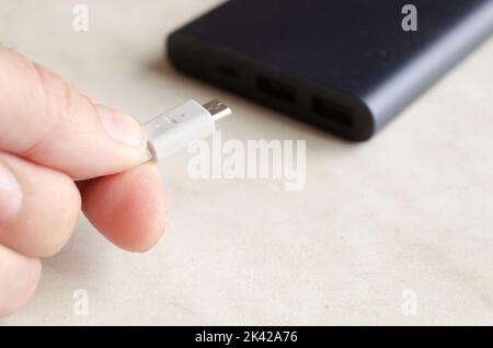 a man holds a charging cable for charging a powerbank Stock Photo