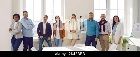Friendly and joyful startup colleagues working together in office in modern business center. Stock Photo