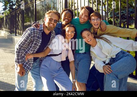 Cheerful group of youth best friends having fun posing for photo while walking on city streets. Stock Photo